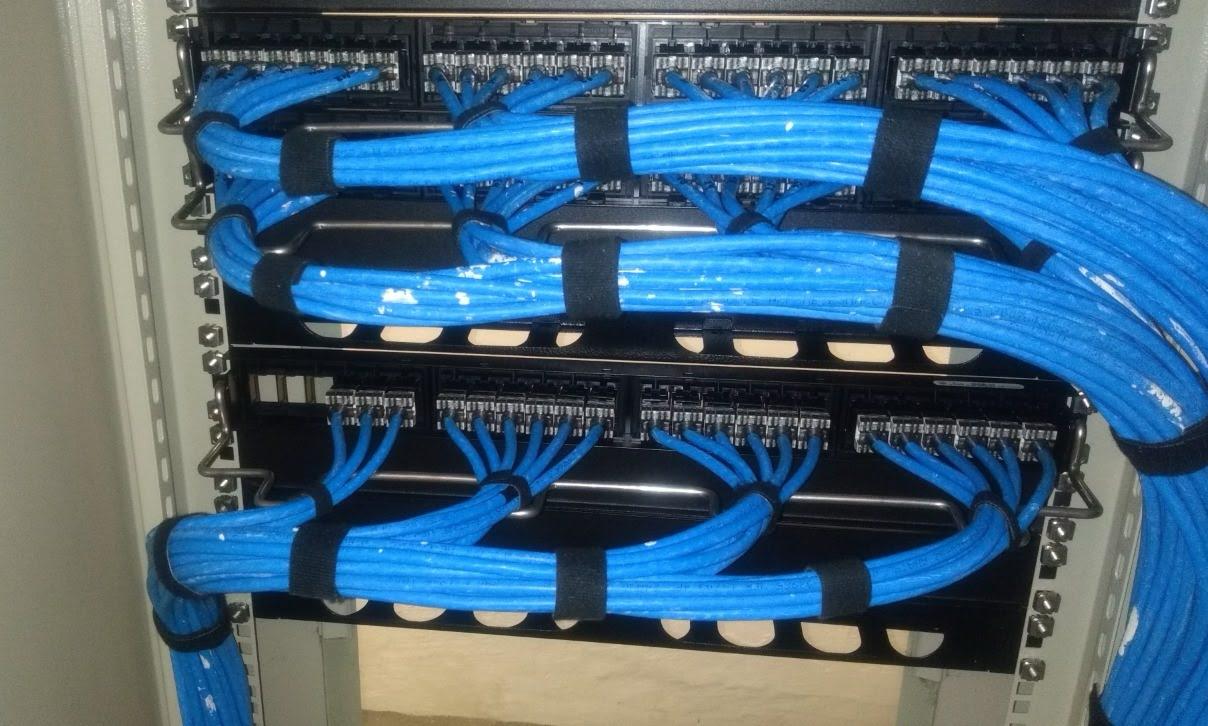 Cabos de rede azuis organizados e presos com velcro em patch panels de rack