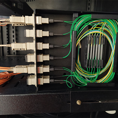 Interior de distribuidor óptico com conectores SC acoplados e pigtails verde e amarelo acondicionados em bandeja